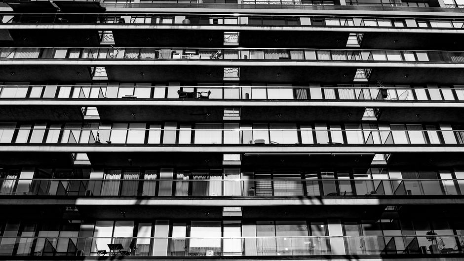 Symmetrical view of a modern apartment building facade captured in black and white.