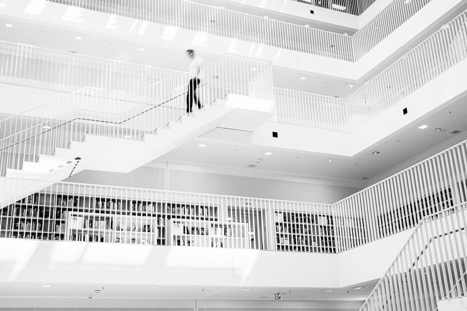 Modern library with a person walking down stairs, captured in black and white.