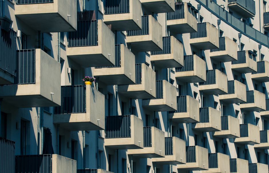 A modern building with geometric balconies and a lone flower pot adds color.