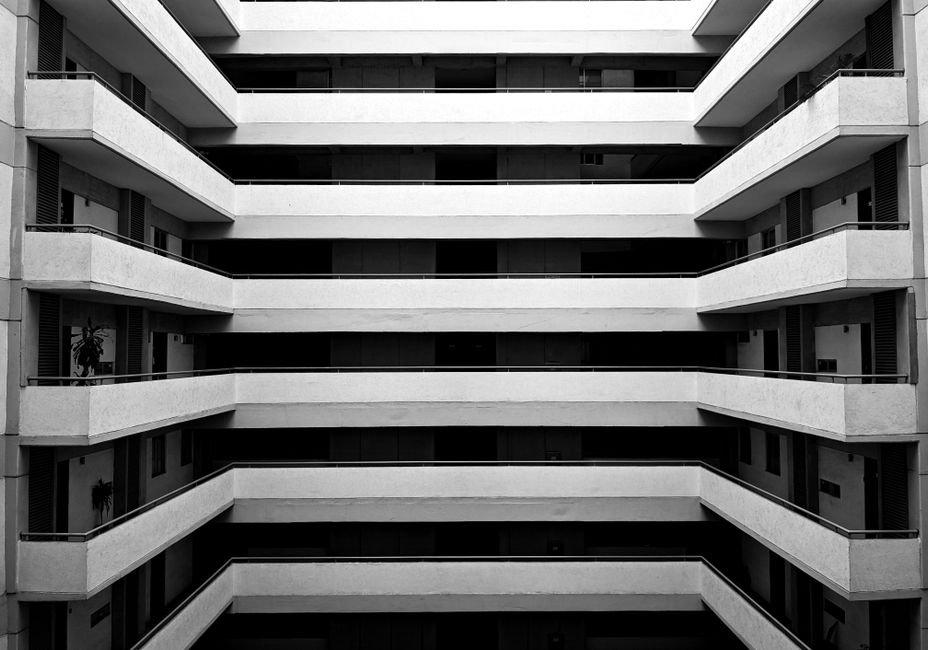 A striking black and white view of a symmetrical apartment building's balconies.